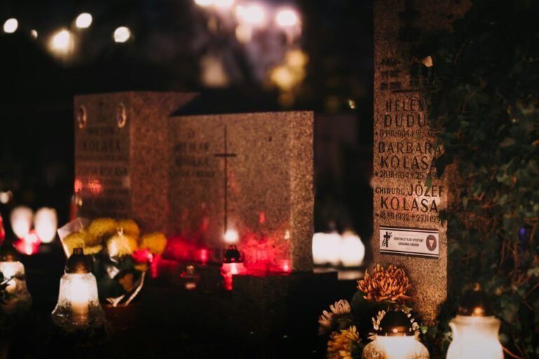 lápidas de un cementerio con velas encendidas y flores por la noche