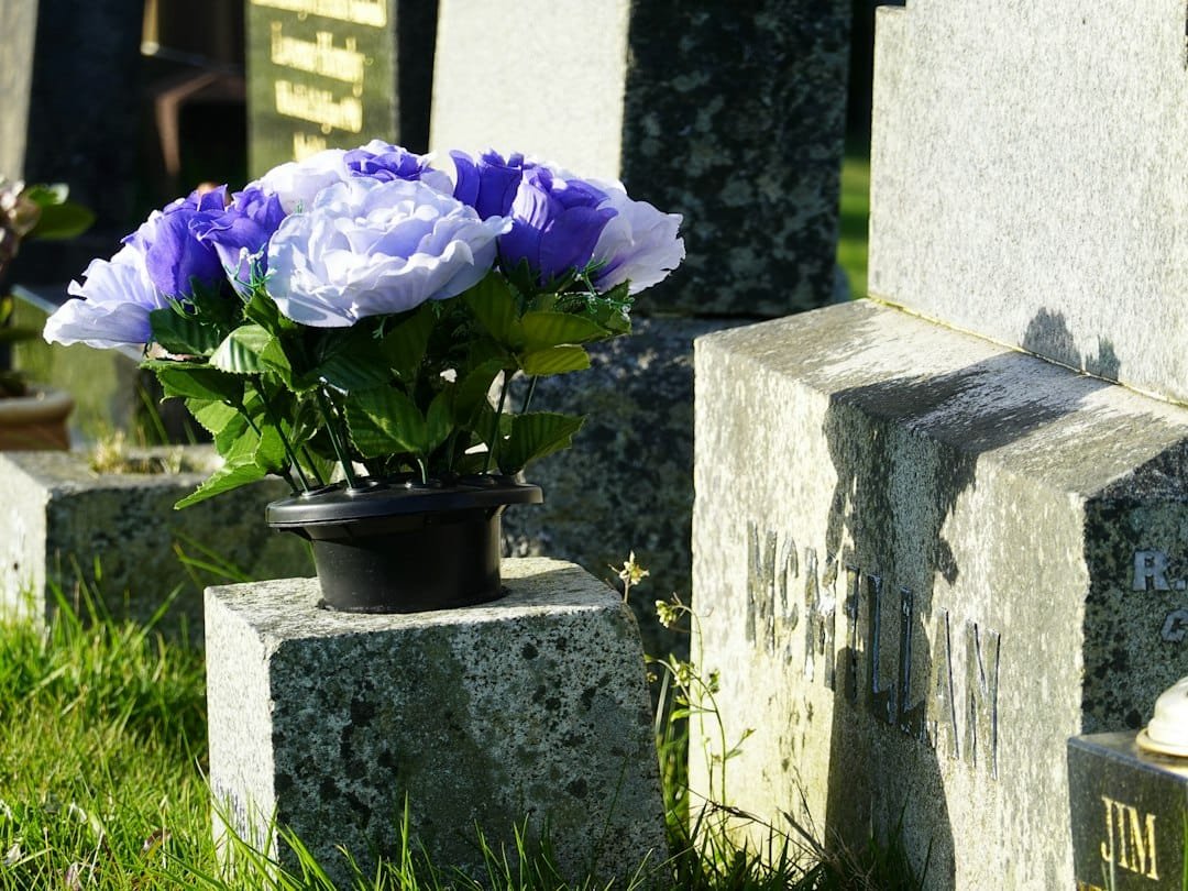 Ramo de flores moradas y blancas sobre una lápida en un cementerio